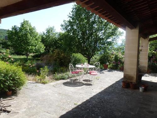 d'une terrasse avec une table et des chaises dans le jardin. dans l'établissement Au coeur du luberon, Grande villa avec piscine, et parc arboré, à Bonnieux