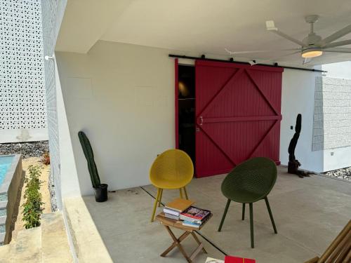 a room with two chairs and a red door at Casa Bajura Bed and Breakfast in Isabela