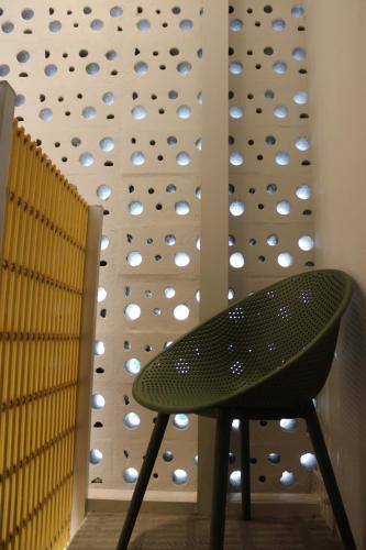 a green chair in front of a climbing wall at Casa Bajura Bed and Breakfast in Isabela