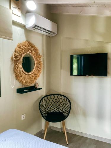 a room with a chair and a mirror on the wall at Gardy rooms in Nea Kalikratia
