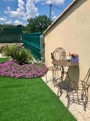 a patio with a table and chairs and flowers at La Maison des Tarentes in Brignoles
