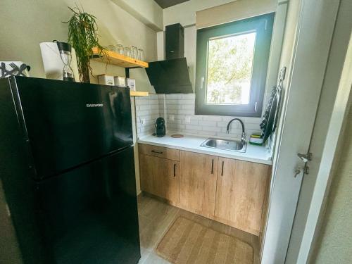 a kitchen with a black refrigerator and a sink at Gardy rooms in Nea Kalikratia