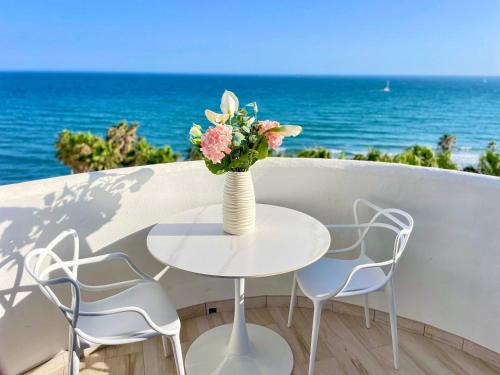ein Tisch und Stühle mit einer Vase mit Blumen darauf in der Unterkunft Algaida, beach apartment in Mijas Costa