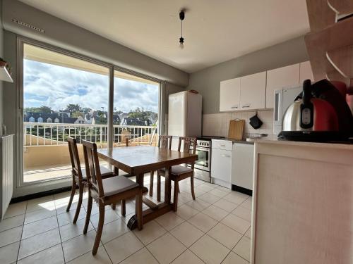 une cuisine avec une table et des chaises ainsi qu'une grande fenêtre dans l'établissement 401 - Appart T2 à 50m de la belle plage de Caroual, à Erquy