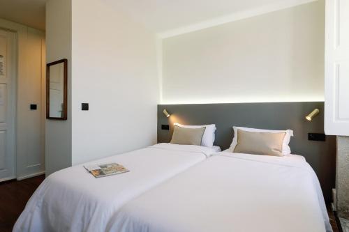 Una cama blanca grande con dos almohadas en una habitación. en Cosme Apartments by Olala Homes, en Oporto