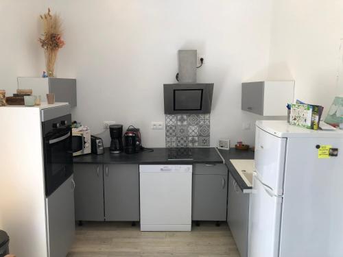une cuisine avec des appareils blancs et un comptoir noir dans l'établissement Maison au Calme Climatisée avec spa de mai à fin septembre, à Royan