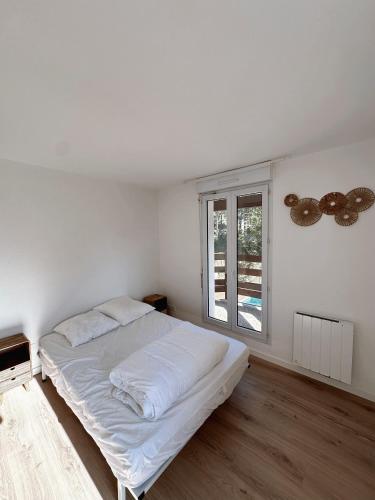 une chambre blanche avec un lit et une fenêtre dans l'établissement Magnifique villa face au golf avec piscine au sel, à Lacanau