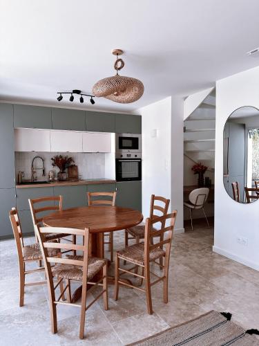 une cuisine et une salle à manger avec une table et des chaises en bois dans l'établissement Magnifique villa face au golf avec piscine au sel, à Lacanau