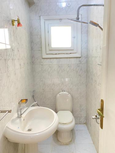 a white bathroom with a toilet and a sink at 50% Off. 2BR , 2BR Ground floor with pool view, private beach access, security 24/7 شاليه ٢ غرفه ، ٢ حمام ف الدور الارضي قدام جنينه و حمام السباحه مباشره ، شاطيء خاص بالقرية و أمن ٢٤ ساعه و مسجد خاص in Dawwār Muḩammad Abū Shanab