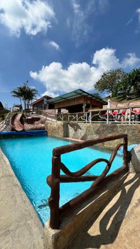 a wooden bench in front of a swimming pool at Hotel Bar Restaurante IL Rifugio in Poás