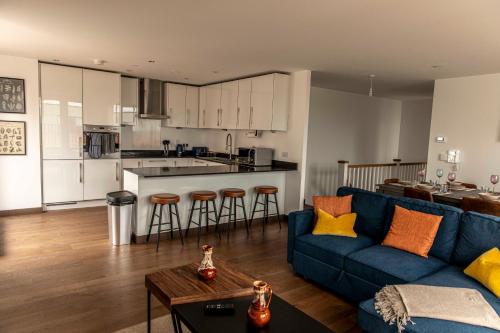 a living room with a blue couch and a kitchen at Maidstone Luxury Penthouse 3 bedroom apartment & parking in Maidstone