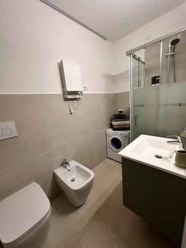 a bathroom with a toilet and a sink and a washing machine at La Stella Bilocale con balcone in Ponte di Legno