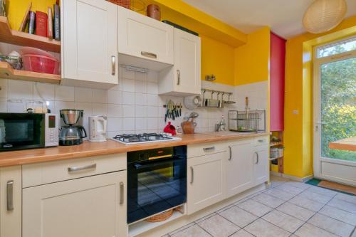 d'une cuisine avec des placards blancs et des murs jaunes. dans l'établissement Maison Albizia, au Croisic