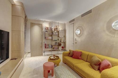 - un salon avec un canapé jaune et une étagère dans l'établissement 671 Suite Bon Marché - Superbe Appartement à Paris, à Paris
