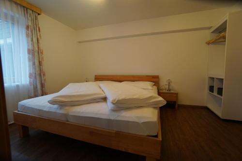 Schlafzimmer mit einem Bett mit weißer Bettwäsche und einem Fenster in der Unterkunft Ferienwohnung Fam.Maria Geiler in Heinfels