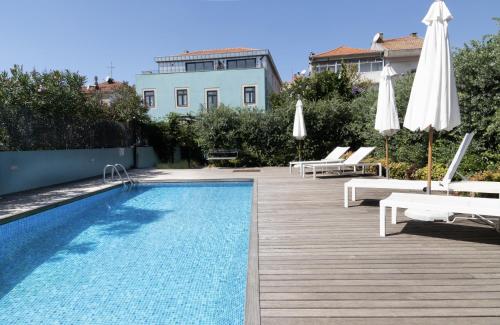 a swimming pool with chairs and umbrellas next to a building at North Side in Porto