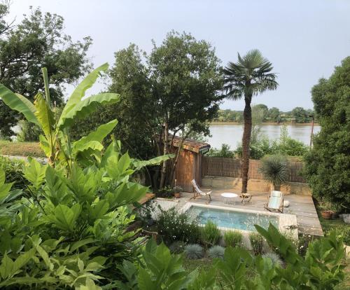 une piscine dans un jardin avec des arbres et une rivière dans l'établissement Songes au lit du fleuve, à Cambes