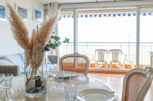 une table de salle à manger avec un vase avec de l'herbe dans l'établissement Appartement avec vue sur la baie des Sables d'Olonne - 4 personnes, à Les Sables-dʼOlonne