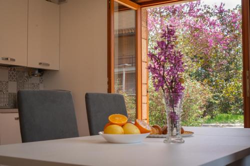 a table with a bowl of oranges and a vase of flowers at Villa Rosa in Castiglione del Lago