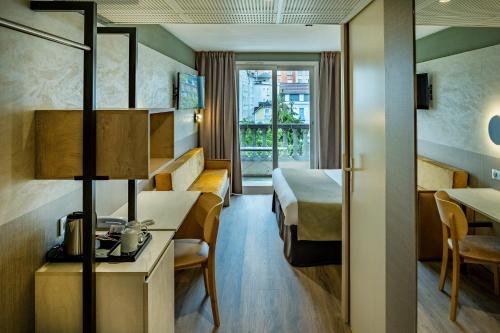 a hotel room with a bed and a table at H&ocirc;tel La Solitude in Lourdes
