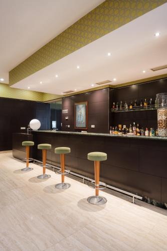 a bar with three stools in front of a counter at Hotel Ciudad de Valladolid in Valladolid