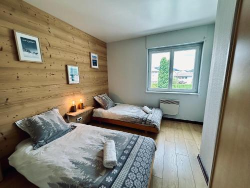 une chambre avec deux lits et une fenêtre dans l'établissement La Perle de l'Eau - au bord du lac, à Gérardmer