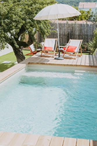 a swimming pool with two chairs and an umbrella at Ti Noémia - casa de vila in Minde