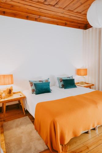 a bedroom with a large bed and a wooden ceiling at Ti Noémia - casa de vila in Minde