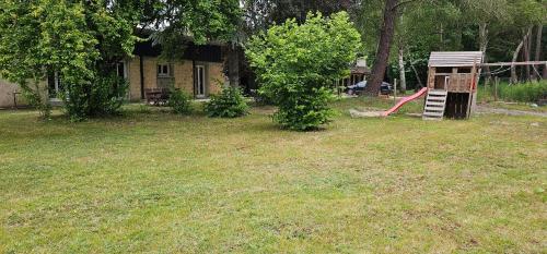 a yard with a playground in front of a house at Le haras de gus et lulu in Guémardières