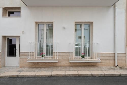 three windows on a white building with flowers in them at Quattro Perle in Polignano a Mare