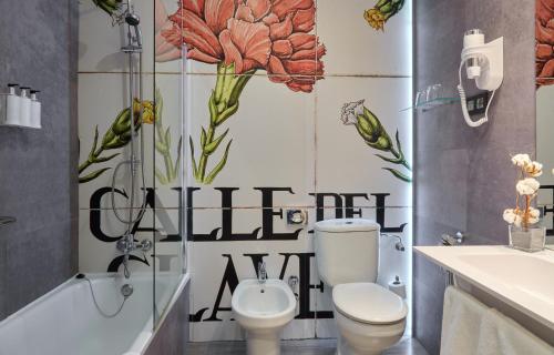 a bathroom with a toilet and a tub and flowers on the wall at Hotel Puerta de Toledo in Madrid