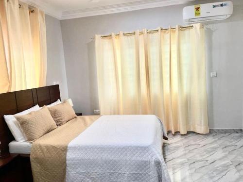 a bedroom with a bed and a couch and curtains at Red Brick Apartments - In Central Accra - 15 Mins To Airport in Accra