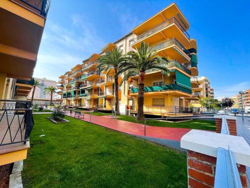 an apartment building with palm trees in front of it at Palm Beach by Unik Vacation in La Pineda