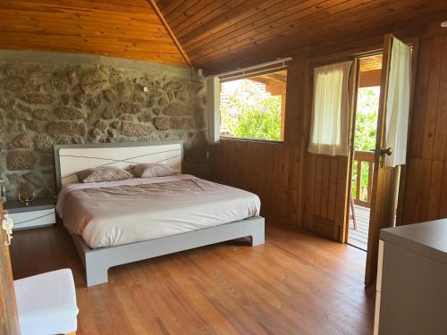 a bedroom with a bed and a stone wall at Quinta de Argens in Cinfães