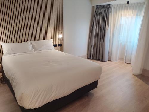 a bedroom with a large white bed and a window at Hotel Sercotel Cuatro Postes in Avila