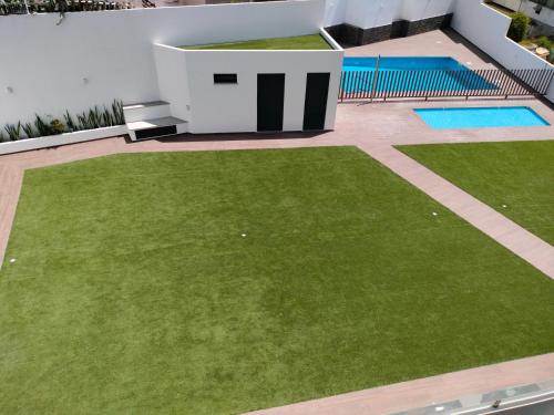 a garden with green grass next to a building at Apartamento Flow Living, com piscina, em Olhão in Olhão