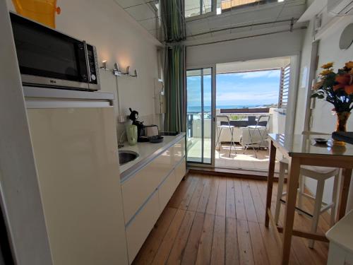 Il comprend une cuisine équipée d'un four micro-ondes et d'une table avec un balcon. dans l'établissement Studio 121 B, Port Nature au village naturiste, au Cap d'Agde