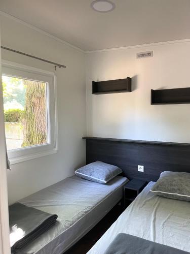une chambre avec deux lits et une fenêtre dans l'établissement Mobil-home 3 chambres Premium - Camping la Faloise, à Angicourt