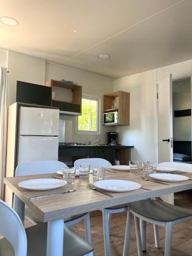 - une cuisine avec une table en bois et des chaises blanches dans l'établissement Mobil-home 3 chambres Premium - Camping la Faloise, à Angicourt