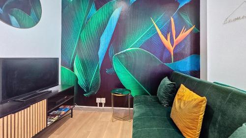 a living room with a green couch and a tv at L'Oiseau du paradis, entre gare et centre ville, rez-de-chaussée, avec terrasse et parking privé in Moulins