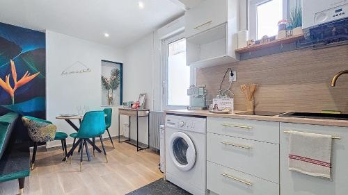 a kitchen with a washing machine and a table at L'Oiseau du paradis, entre gare et centre ville, rez-de-chaussée, avec terrasse et parking privé in Moulins