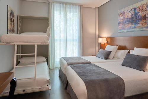 a hotel room with two beds and a window at Hotel Puerta de Toledo in Madrid