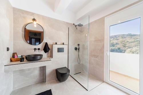 a bathroom with a sink and a shower with a mirror at Villa Tranquility in Psinthos