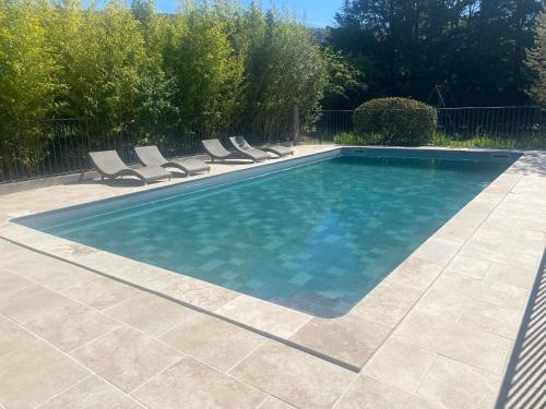 a swimming pool with chairs in a yard at Villas de La Ferme Du Gros Noyer in Malaucène