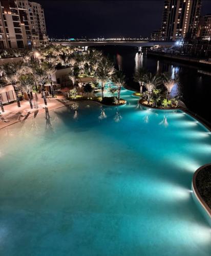 a large pool of blue water at night at Burj Khalifa view & Creek sea view in Dubai