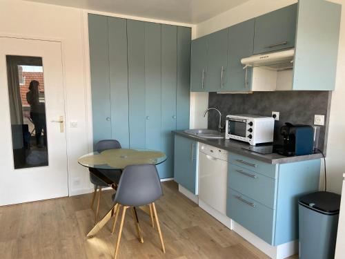 une cuisine avec des placards bleus et une table avec des chaises dans l'établissement Lily blue, à Vichy