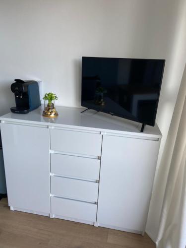 - une commode blanche avec une télévision en haut dans l'établissement Lily blue, à Vichy