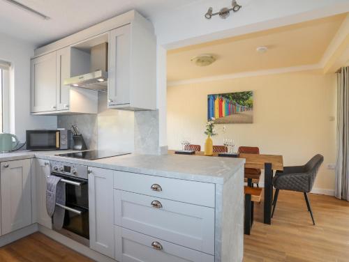 a kitchen with white cabinets and a dining table at Hafan Deg in Pwllheli