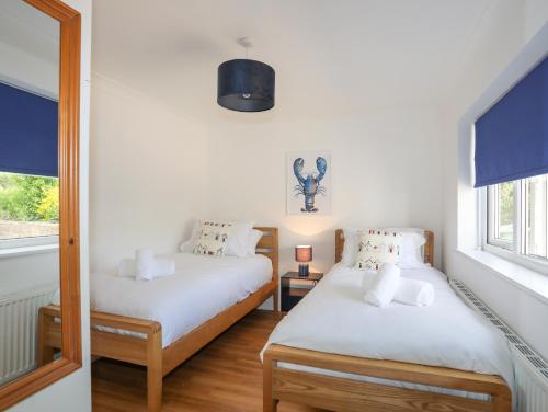 a bedroom with two beds and a mirror at Hafan Deg in Pwllheli