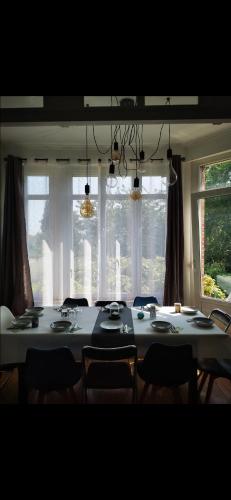 a dining room with a table and chairs and windows at Grande maison tout confort, billard et spa -en saison in Lys-lez Lannoy